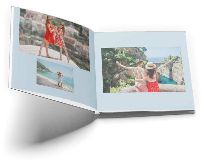 The Amalfi book open at pages 14 and 15: two girls in front of a hillside town and a girl at the sea on the left, a couple above the Furore gorge on the right